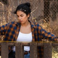 woman measuring the length of a part of a wooden fence she constructed after looking at different types of wood