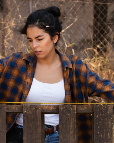 woman measuring the length of a part of a wooden fence she constructed after looking at different types of wood