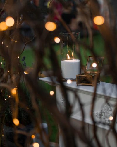 Candle on table seen through vines and fairy lights illustrating Valentine's Backyard Bliss