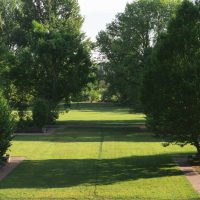 A well-designed garden with mature trees, layered planting, open lawn, and pathways creating a balanced landscape.